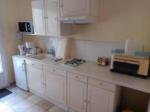 uma cozinha com armários brancos e uma bancada em Anduze Gîte Les Lauriers au "Petit Clos des Cigales" em Massillargues-Attuech