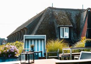 une maison au toit de chaume avec des tables et des chaises dans l'établissement Boutique Suites Sylt - Kliffkante - Opening August 2023, à Kampen