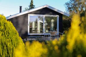 uma casa com uma grande janela com uma mesa e cadeiras em Bright summer house close to the beach and water em Holbæk