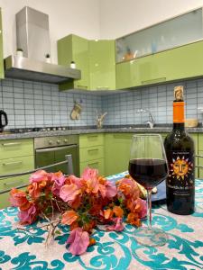 a glass of wine and flowers on a table in a kitchen at Alpha22 Apartment in Giardini Naxos