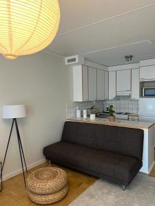 a living room with a couch in front of a kitchen at Modern and cozy apartment with Sauna in Espoo