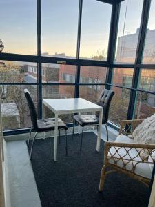 a white table and chairs in a room with windows at Modern and cozy apartment with Sauna in Espoo