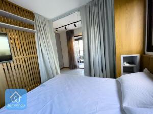 a bedroom with a large white bed and a window at Apartamento com linda vista mar no Smart Barra 2 in Salvador