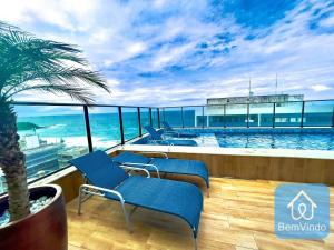 a balcony with blue chairs and a swimming pool at Apartamento com linda vista mar no Smart Barra 2 in Salvador