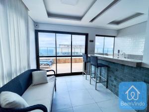 a living room with a couch and a kitchen with a view at Apartamento com linda vista mar no Smart Barra 2 in Salvador