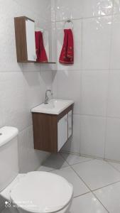 a bathroom with a toilet and a sink and red boots at Casa Completa com Garagem a 400mts da basilica in Aparecida