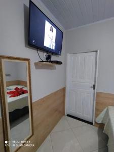 a room with a tv on the wall and a mirror at Casa Completa com Garagem a 400mts da basilica in Aparecida