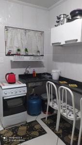 a kitchen with a stove and two chairs in it at Casa Completa com Garagem a 400mts da basilica in Aparecida