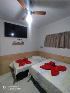 two beds in a room with a ceiling fan at Casa Completa com Garagem a 400mts da basilica in Aparecida