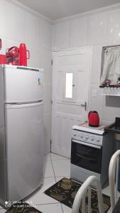 a kitchen with a white refrigerator and a stove at Casa Completa com Garagem a 400mts da basilica in Aparecida