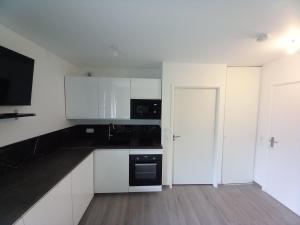 a kitchen with white cabinets and a black appliance at Le Cocon Vert in Rueil-Malmaison