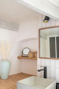 y baño con lavabo blanco y espejo. en Maison typique et de caractère au cœur d'un des plus beaux villages de France en La Roque-sur-Cèze