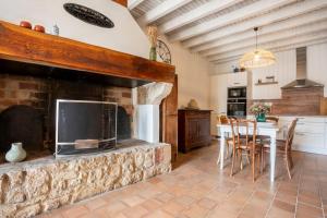 cocina con chimenea de piedra, mesa y sillas en Maison typique et de caractère au cœur d'un des plus beaux villages de France en La Roque-sur-Cèze