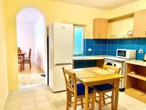 a kitchen with a wooden table and a kitchen with a refrigerator at Sea view country house in Prčanj