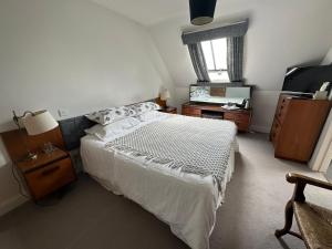 1 dormitorio con cama blanca y espejo en Greenhill Farm Barn B&B, en Sutton under Brailes