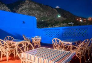 Habitación azul con mesas, sillas y una montaña en CASA TROUSSI, en Chefchaouen