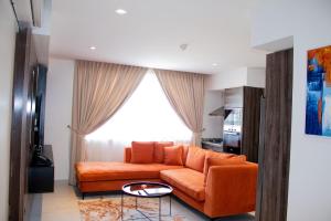 an orange couch in a living room with a window at Iconic Shortlets in Lagos