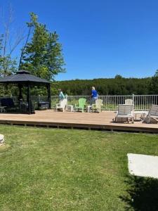 a wooden deck with a gazebo and chairs and people at 2 bdrm country cottage - The Bait - Rosewood cottages in Southampton