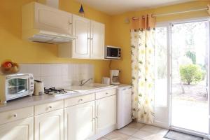 a kitchen with white cabinets and a sink and a window at Anduze Gîte Les Pins au "Petit Clos des Cigales" in Massillargues-Attuech