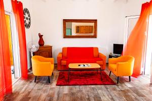 a living room with a red couch and two orange chairs at Les gites du plateau de gissac in Sainte-Anne