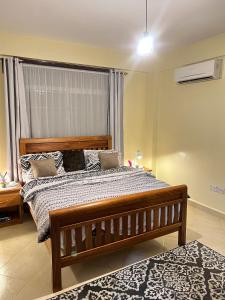 1 dormitorio con cama grande de madera y ventana en Comfort Oasis, en Dar es Salaam