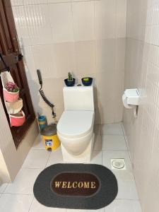 a bathroom with a white toilet and a welcome mat at Comfort Oasis in Dar es Salaam