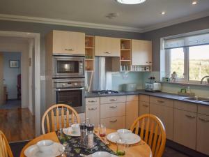 a kitchen with a wooden table and chairs and a table and a kitchen with at Seaview in Barvas