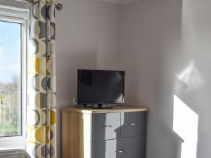 a flat screen tv sitting on top of a dresser at Seaview in Barvas