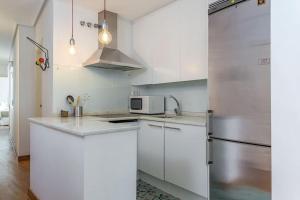 cocina con armarios blancos y nevera de acero inoxidable en MAD COCO Vintage Apartment Madrid en Madrid