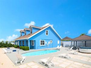 una casa azul con piscina y sillas en Southwinds Vacation Home en East End