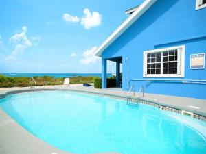 una gran piscina frente a una casa azul en Southwinds Vacation Home en East End