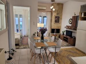 uma cozinha e sala de estar com uma mesa de vidro e cadeiras em MarGe Apt em Arta