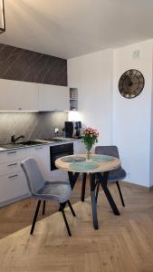 a kitchen with a table and two chairs with a vase of flowers at Apartament Sienkiewicza 22 in Zamość