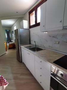 a kitchen with white cabinets and a stainless steel refrigerator at Mountain Summer Houses - River Sound in Panayia