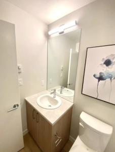 a bathroom with a sink and a toilet and a mirror at Perfect Brand New Condo In The Heart of Sidney in Sidney