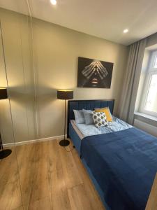 a bedroom with a blue bed and a window at Łódź4HOME Apartament in Łódź