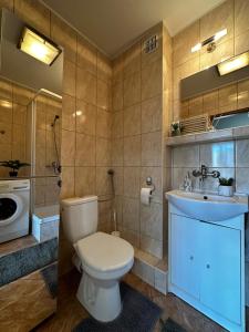 een badkamer met een toilet, een wastafel en een wasmachine bij Sopot Sea Apartments in Sopot
