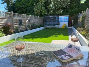 two glasses of wine sitting on a table with a book at Three Bedroom Family home with garden in Walthamstow in London