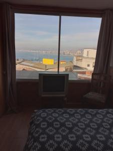 1 dormitorio con ventana grande con vistas al océano en Hostal Armando, en Valparaíso