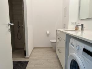 a white bathroom with a washing machine and a toilet at Luxury Waterfront Apartment in Berlin