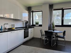 Luxury Waterfront Apartment في برلين: مطبخ مع دواليب بيضاء وطاولة وكراسي