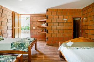 1 dormitorio con 2 camas y pared de ladrillo en Arca Tayrona Restaurant & Hostal en Santa Marta