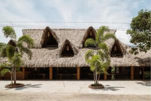 un edificio de paja con palmeras delante en Arca Tayrona Restaurant & Hostal en Santa Marta