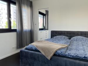 a bedroom with a bed with a blue comforter and windows at Luxury Waterfront Apartment in Berlin
