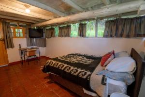 a bedroom with a bed and a television in it at Cabaña Kinti Q'umir Umiña en Kinti Wasi in Los Baños del Inca