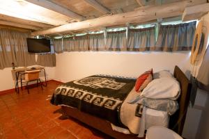 Dormitorio con cama, escritorio y TV en Cabaña Kinti Q'umir Umiña en Kinti Wasi, en Los Baños del Inca