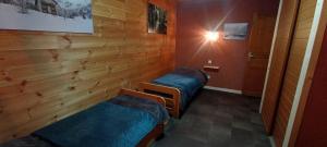 two beds in a room with wooden walls at Chalet les Alpes - Le Sapey in Vénosc