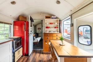 a kitchen with a red refrigerator and a wooden table at Tiny House Train-Eco stay in Upper Hutt
