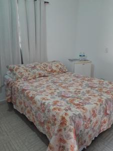 Recanto Suítes في أرارواما: غرفة نوم مع سرير وبطانية مزهرة