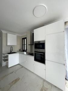 a white kitchen with white cabinets and appliances at Sunset of Duke#Luxury Costa Adeje in Adeje